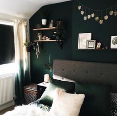 a bedroom with dark green walls and white fur on the bed