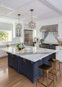 a large kitchen island with two stools in front of it and an oven on the other side