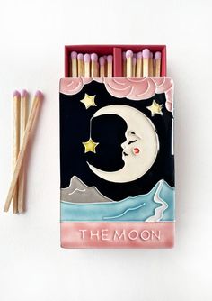 matchestick holder with the moon and stars on it next to two matchsticks