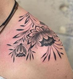 a woman's shoulder with flowers and leaves tattoo on her left side breast area