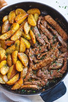 steak and potatoes in a cast iron skillet on a white table with a blue towel