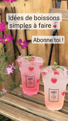 two pink drinks sitting on top of a wooden bench