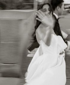 a bride and groom are running down the street in black and white, with motion blurry behind them