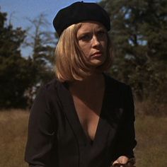 a woman in a black dress and hat on a bike with trees in the background