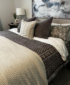 a bedroom with a large painting on the wall above the headboard and bedding