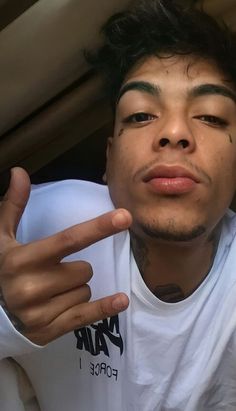 a young man making the peace sign with his hand while wearing a white t - shirt