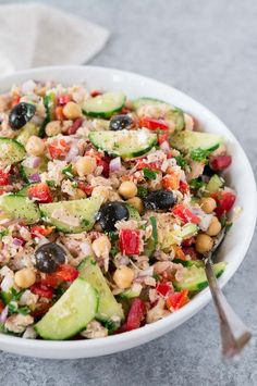 a salad with cucumbers, tomatoes, black olives and chickpeas