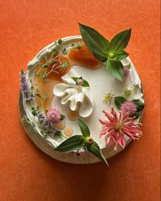 a cake decorated with flowers and leaves on an orange surface