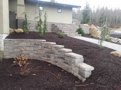 a stone retaining wall in front of a house