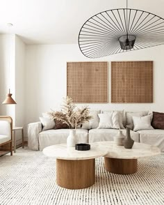 a living room filled with white couches and two round tables in front of them