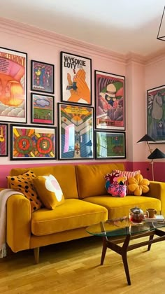 a living room with pink walls and pictures on the wall above it's couch