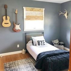 a bed room with a neatly made bed and guitars hanging on the wall above it