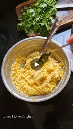 a person mixing food in a bowl on top of a table with utensils