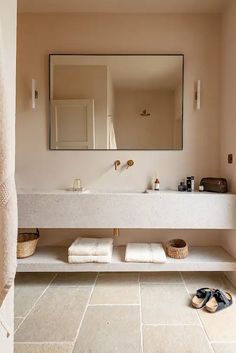 a bathroom with a sink, mirror and towels on the floor in front of it