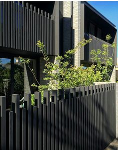 a black fence is in front of an apartment building with trees and bushes on the side