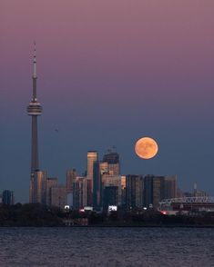 the full moon is setting over the city skyline