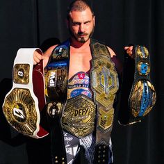 a man in a wrestling suit holding two different types of belts on his chest and shoulders