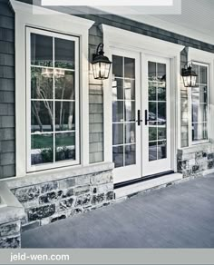 the front door of a house with three windows and two lights on each window sill