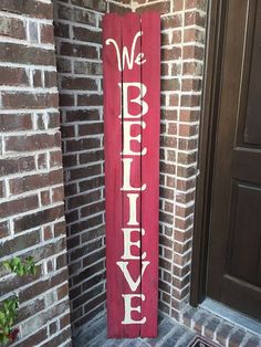 a red wooden sign that says merry christmas on the side of a brick building next to a door