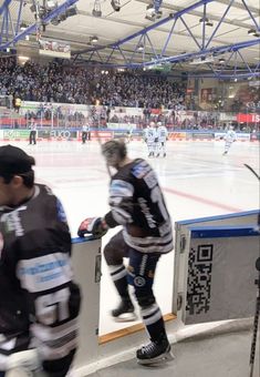 two hockey players on the ice in front of an arena full of people and fans