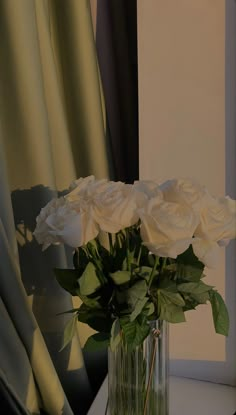 a vase filled with white roses on top of a table