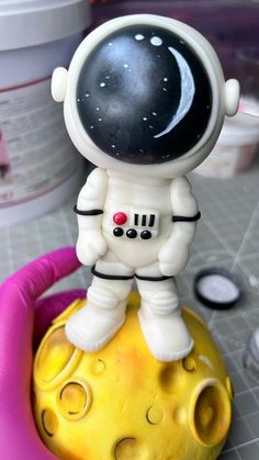 a small toy is sitting on top of a yellow object in the shape of an astronaut