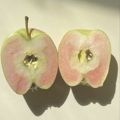 an apple cut in half sitting on top of a white table next to another apple