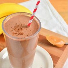 a smoothie in a glass on a plate with a striped straw next to it