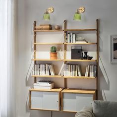 a living room filled with furniture and bookshelves next to a wall mounted lamp