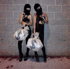 two people wearing masks and holding bags in front of a brick wall with the caption'miss universo '