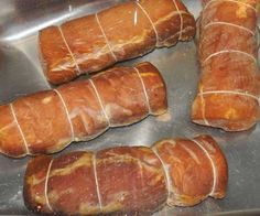 four pieces of meat wrapped in plastic sitting on top of a stainless steel tray,