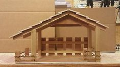 a wooden dollhouse is sitting on a table in front of cardboard boxes and other items