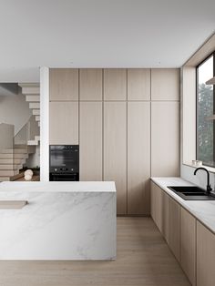 a modern kitchen with marble counter tops and wooden stairs leading up to the second floor