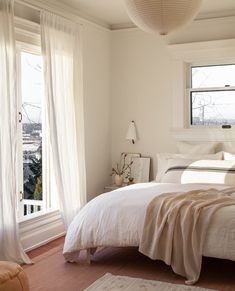 a bedroom with a bed, window and rug in front of the bed is white