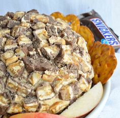 an apple and some chips on a plate with milk caramels in the background