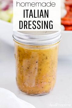 a jar filled with homemade italian dressing next to salad