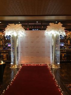 a red carpet with lights on the floor and white flowers in vases at the end