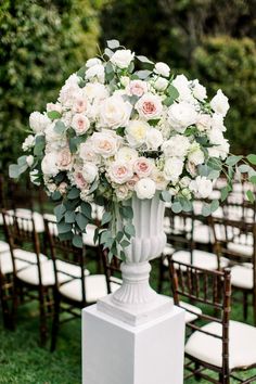 a vase filled with white and pink flowers sitting on top of a lush green field