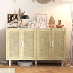 a cabinet with some pictures and vases on top of it in a living room