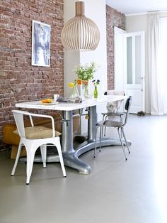 a dining room table and chairs in front of a brick wall