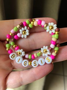 a person holding two bracelets with beads and letters on them in their hands,