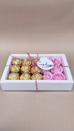 a white box filled with pink roses and chocolates