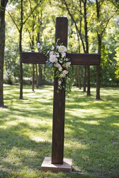 a wooden cross with flowers on it in the grass