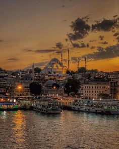 the city is lit up at night with boats in the water