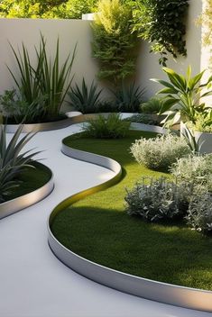 an outdoor garden with grass and plants in the center, surrounded by white concrete walls