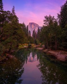 a mountain is in the distance with trees around it and a river running through it