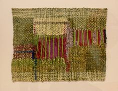 a piece of art that is made out of different colored fabrics and yarns on a white surface