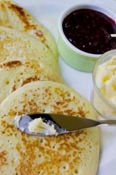 three pancakes on a plate with butter and jelly