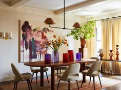 a dining room table with chairs and vases on top of it in front of a painting