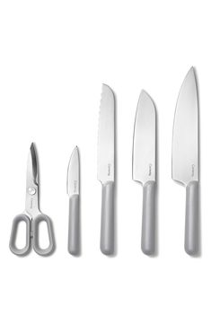 three knives, two scissors and one knife are on a white surface with clippings